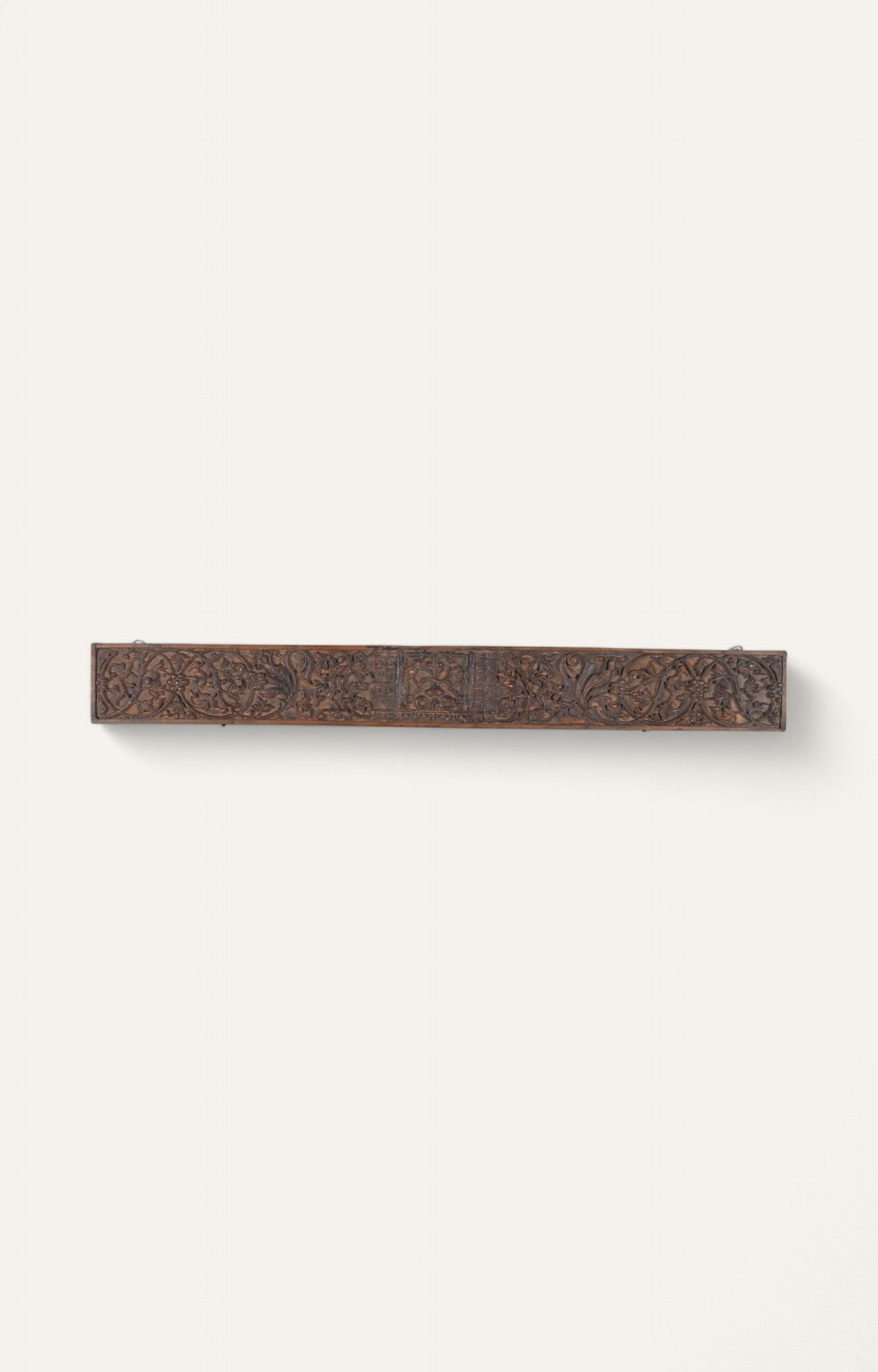 Dark wooden hand-carved panel with central flower medallion and symmetrical scroll design