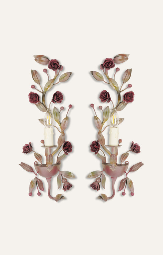 Floral wall sconce with powder pink painted metal and light attached.